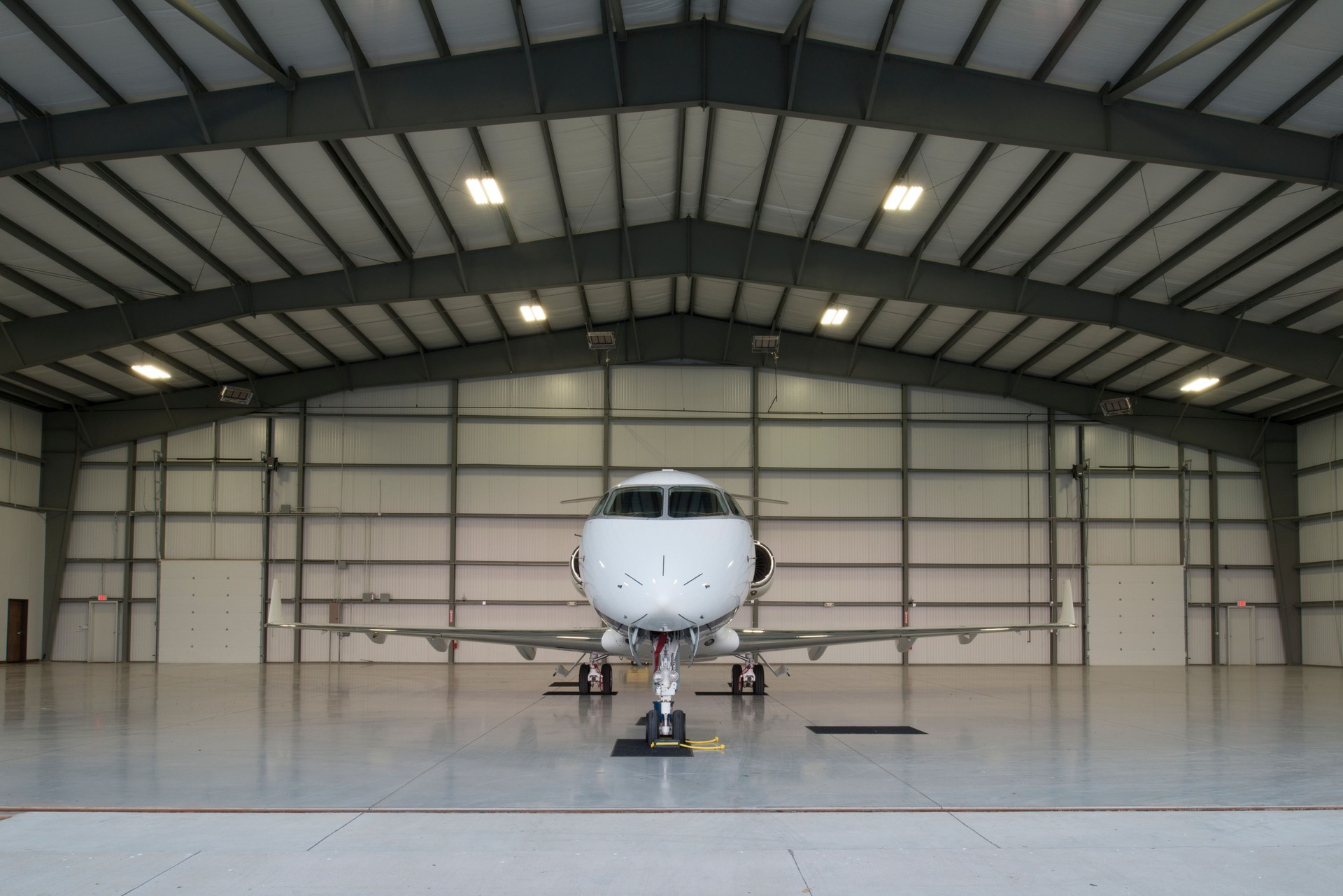 Private jet inside a pre-engineered steel airplane hangar with wide clear-span framing Private jet inside a pre-engineered steel airplane hangar with wide clear-span framing