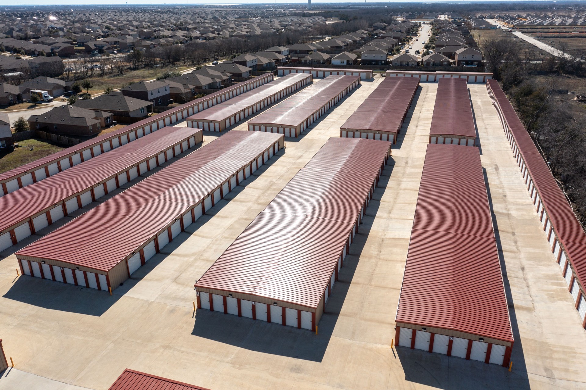 Aerial view of multiple red-roofed mini storage units with drive-up access Aerial view of multiple red-roofed mini storage units with drive-up access